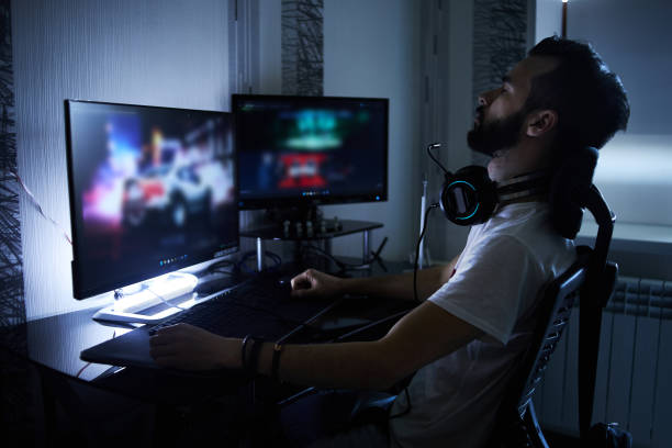 a young 30-year-old gamer is sitting at a computer, playing computer games, nervous, angry, worried.selective focus with low depth of focus - 電競 個照片及圖片檔