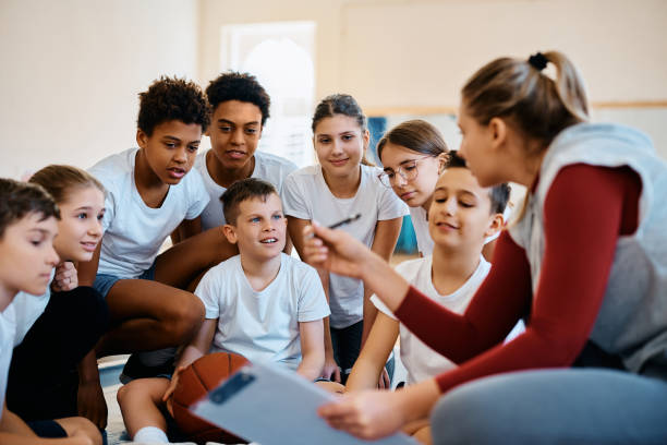 multiracial group of students talking to their sports teacher during basketball class at school. - 電競教育 個照片及圖片檔